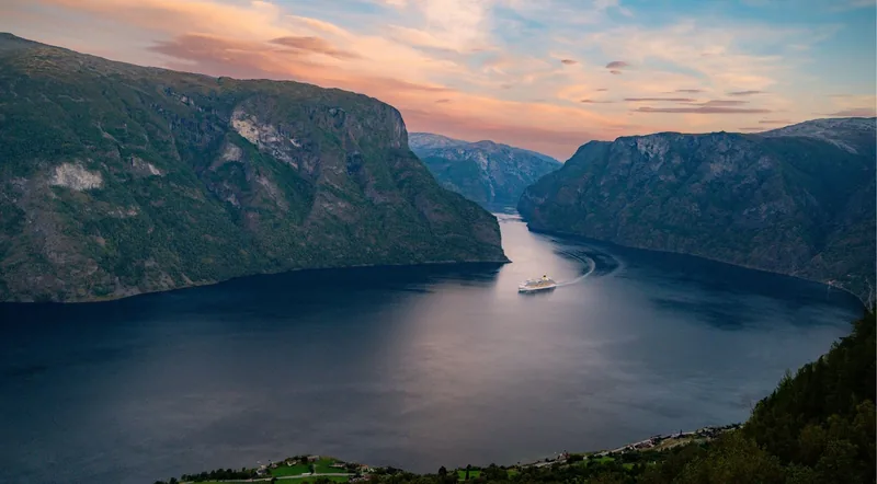 A cruise vessel on the Aurlandsfjord at sunset between steep fjord walls