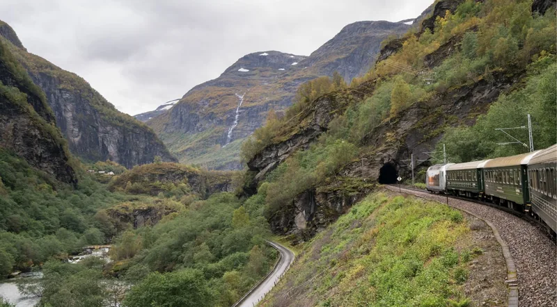 The Flåm Railway curving along a mountainside toward a tunnel